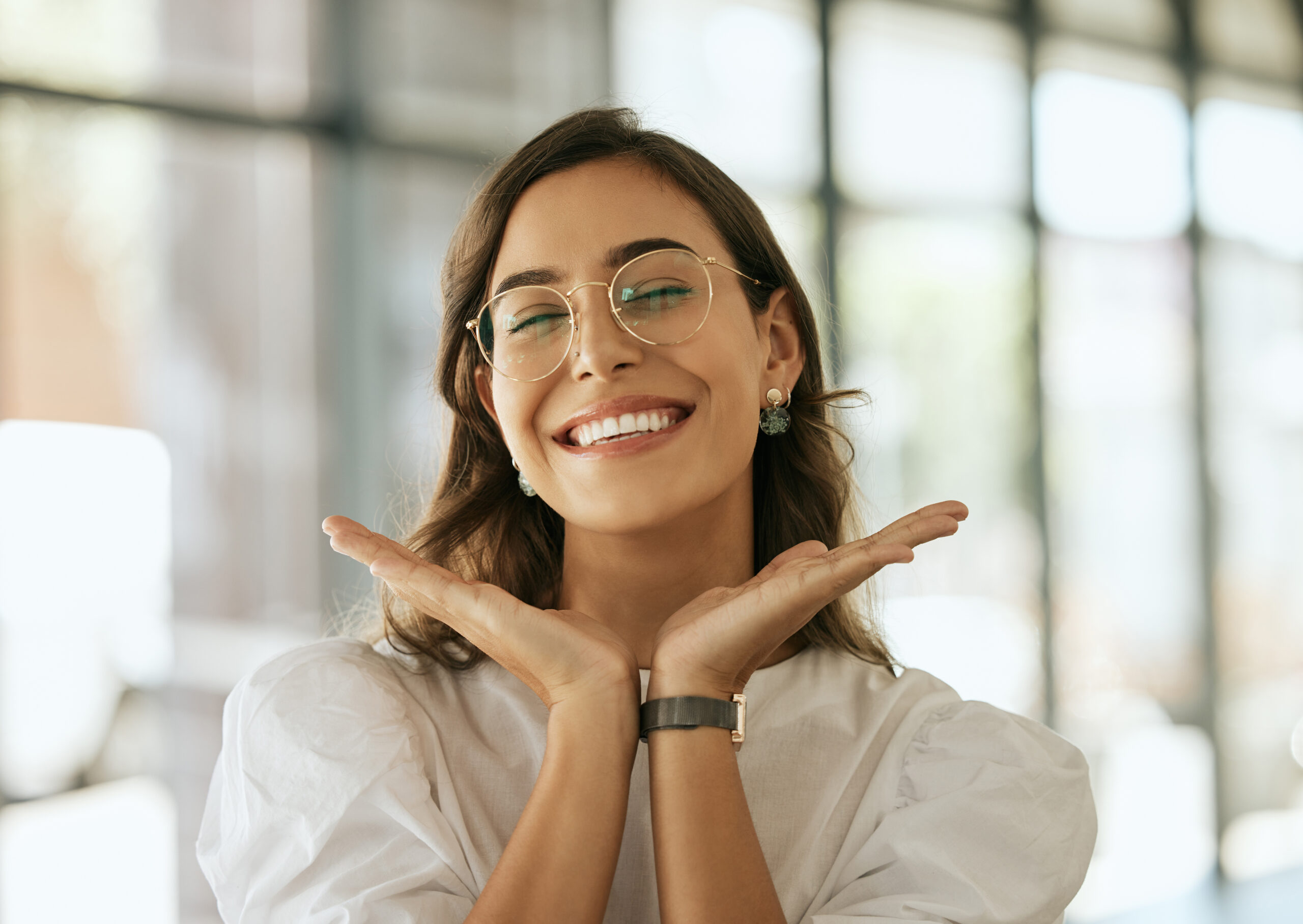 Young professional woman smiling at camera, at work, hands framing face, wearing glasses, Loeb Orthodontics