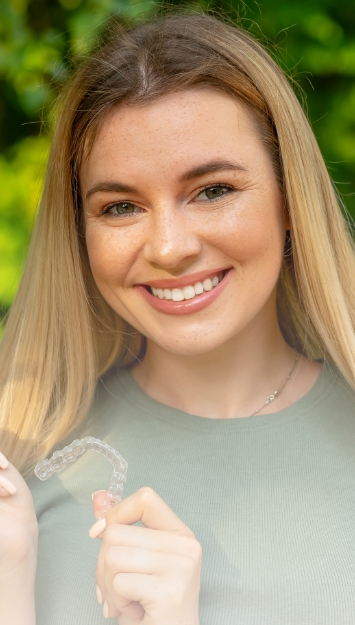 Teen patient holding custom clear aligners for teeth straightening